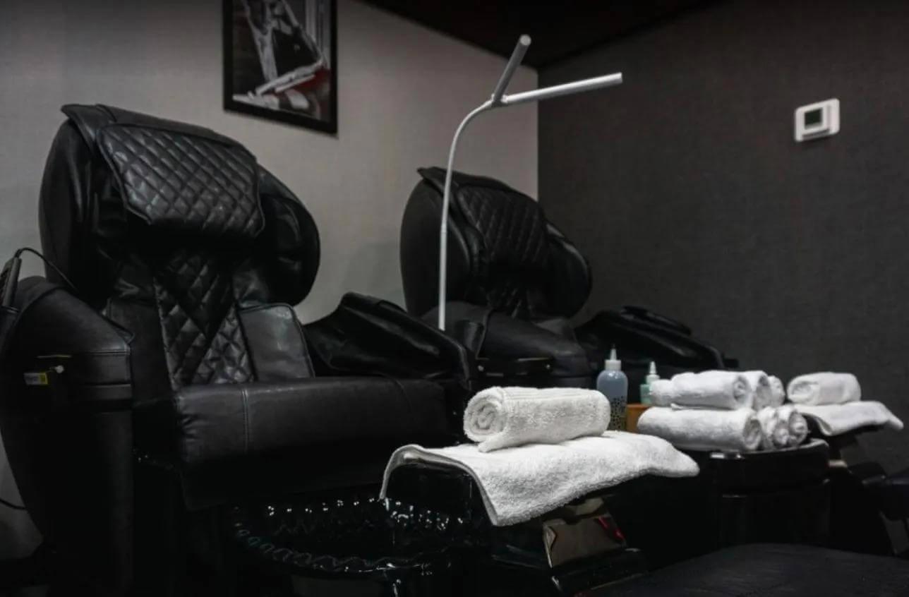 Reclining barber chairs and folded towels inside an ALPHA Men's Spa® grooming lounge